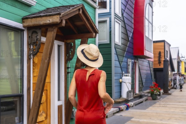 Female tourist wearing a straw hat and a red dress is enjoying a summer day walking down the