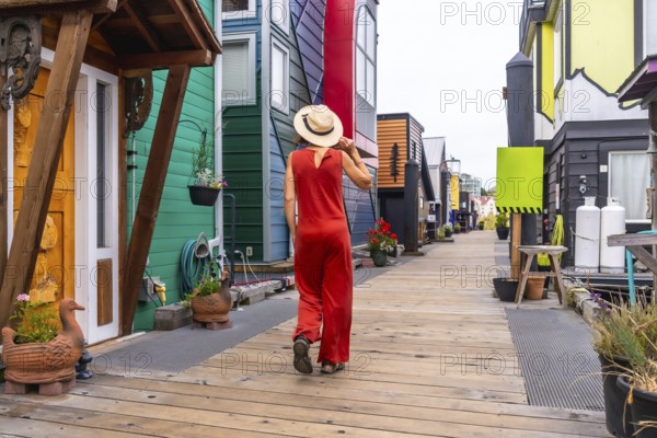 Tourist wearing a straw hat and a red jumpsuit is walking on a wooden walkway exploring the