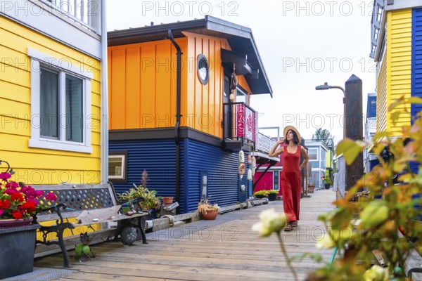 Tourist walking on a wooden walkway. Wearing a straw hat and a red jumpsuit. Exploring the colorful