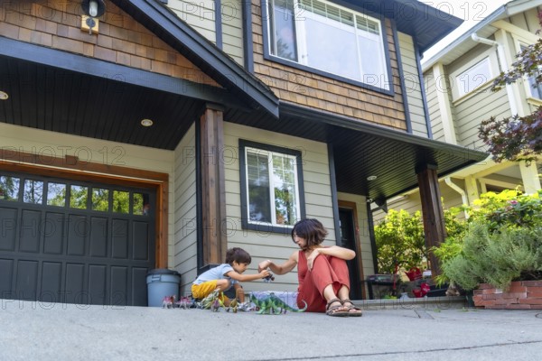 Mother and son bonding over dinosaur toys, enjoying quality time together on the driveway of their
