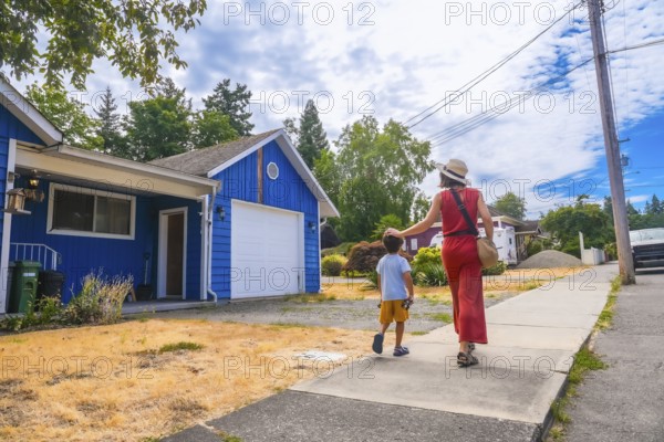 Mother and son strolling down a residential street in chemainus, vancouver island, british