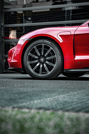 Side view of the front wheel of a red Porsche, focus on rim and body, Porsche Taycan, Deer