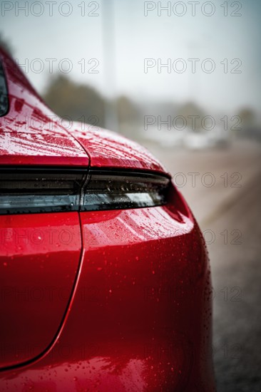 Close-up of a red Porsche with wet body and shiny rear light, Porsche Taycan, Deer Carsharing,