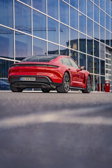 Red car in front of a glass façade with an urban background, Porsche Taycan, Deer car sharing.