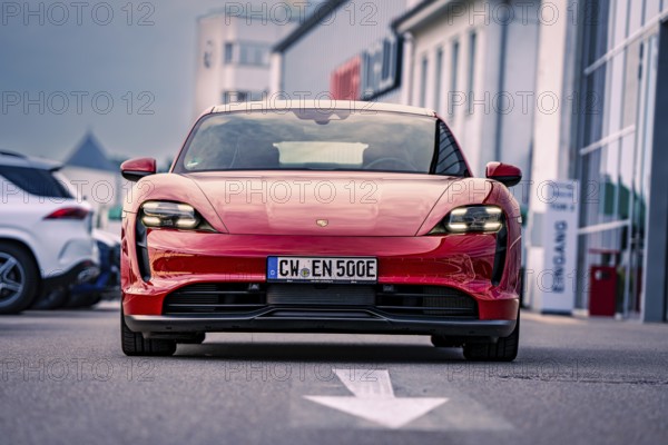 Red car of elegant design parked in an urban square, Porsche Taycan, Deer Carsharing. Calw, Germany