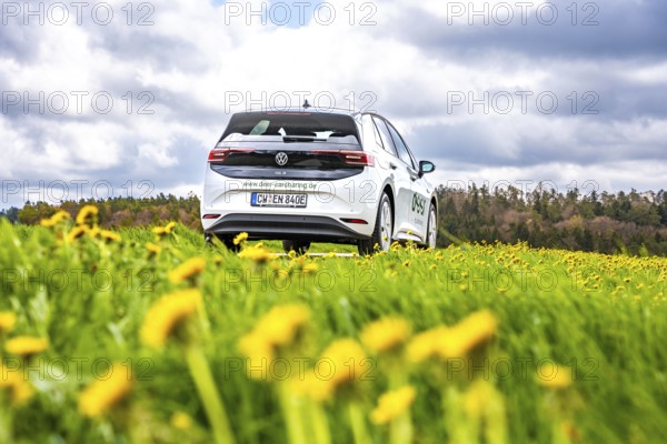 A white car is parked on a flower meadow under a cloudy sky, ID3 VW, deer car sharing. Calw,