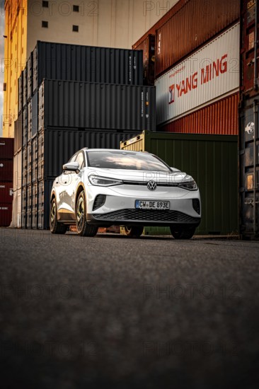 Silver car next to stacked containers at sunset, VW ID4 electric car, Deer Carsharing, Calw,