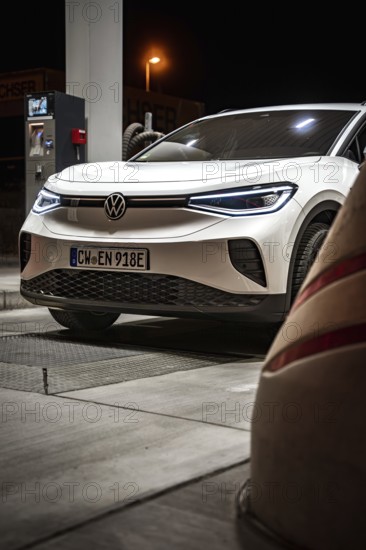 Detailed view of a white Volkswagen at the gas station at night, VW ID4 electric car, Deer