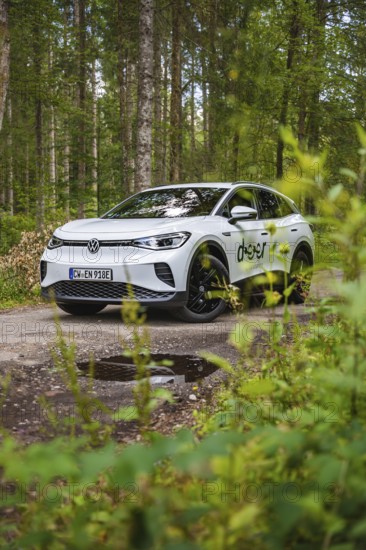 White car in the forest surrounded by green leaves, VW ID4 electric car, Deer Carsharing, Calw,
