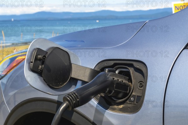 Electric car is being charged at a station by the sea, promoting eco friendly travel and