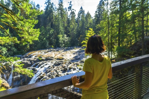 Female tourist admiring englishman river falls in vancouver island, british columbia, canada,