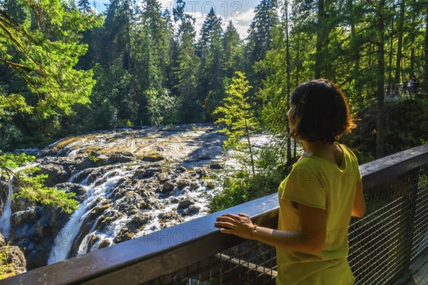 Tourist wearing a yellow t shirt is enjoying the view of englishman river falls from a viewpoint on