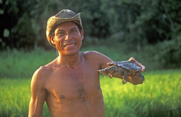 A man who runs a small private zoo near Iquitos on the Amazon shows a turtle, Peru, South America,