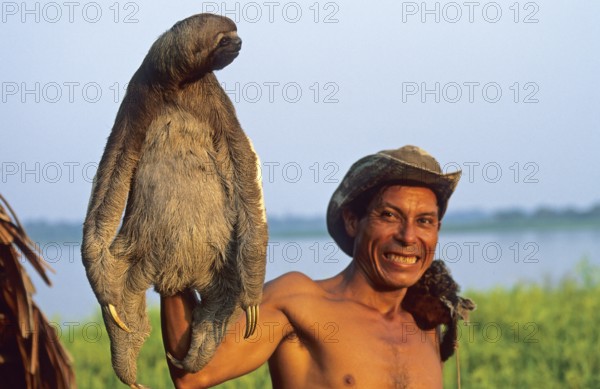 A man who runs a small private zoo near Iquitos on the Amazon shows a sloth, Peru, South America,