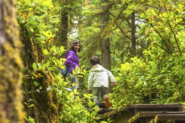 Mother and son enjoying a hike through a lush rainforest trail in ucluelet, located on vancouver