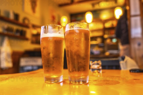 Two glasses of cold craft beer sit on a wooden table in a cozy pub in ucluelet, british columbia,