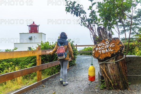 Female tourist walking towards amphitrite point lighthouse on the wild pacific trail near ucluelet