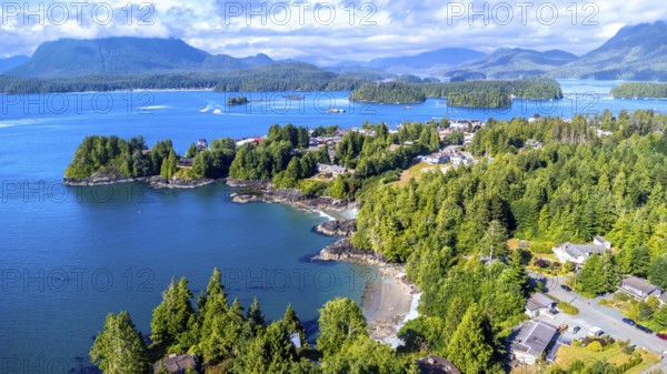 Aerial view capturing tofino on vancouver island, showcasing lush green forests, blue ocean waters,