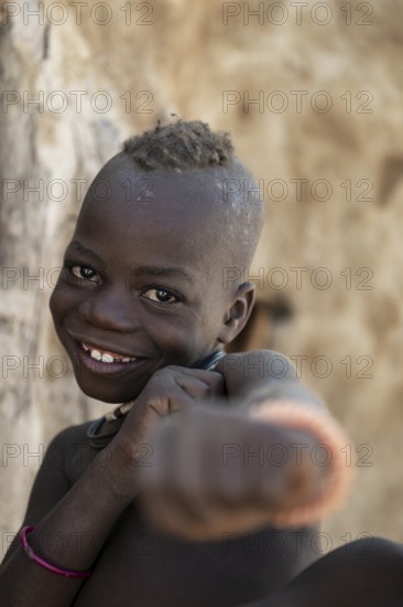 Happy Himba child punching funny at the camera, traditional Himba village, Kaokoveld, Kunene,
