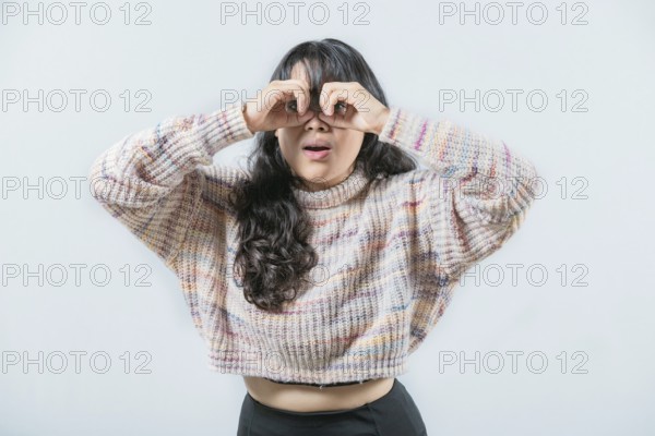 Asian woman making binoculars gesture isolated. Curious asian girl making binoculars gesture