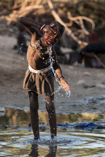 Himba child washing with water on a river, traditional Himba, Kaokoveld, Kunene, Namibia
