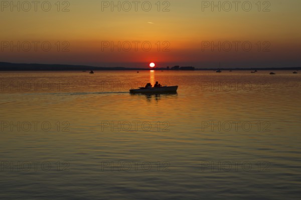 Sunset with boat in the middle of the lake, calm waters, peaceful view, Steinhude Steinhuder Meer