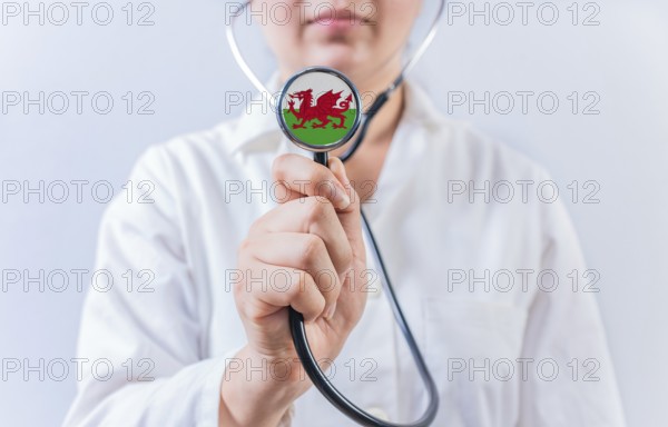 Female doctor holding stethoscope with Wales flag. National health system of Wales