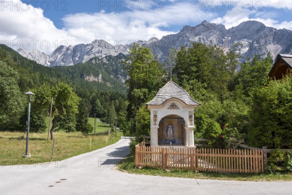 Small trail chapel with the Slovenian Alps in the background, mountaineering village Zgornje