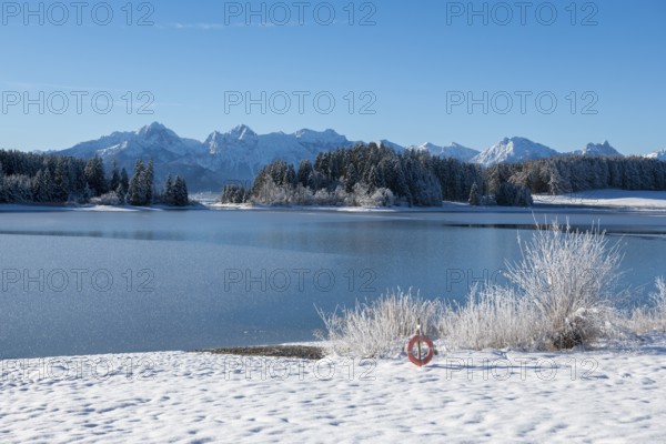 Snowy lake with mountains in the background under blue sky, Forggensee near Roßhaupten, Ostallgäu,