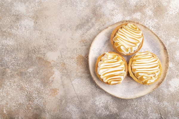 French lemon tart with meringue on brown concrete background, top view, flat lay, copy space