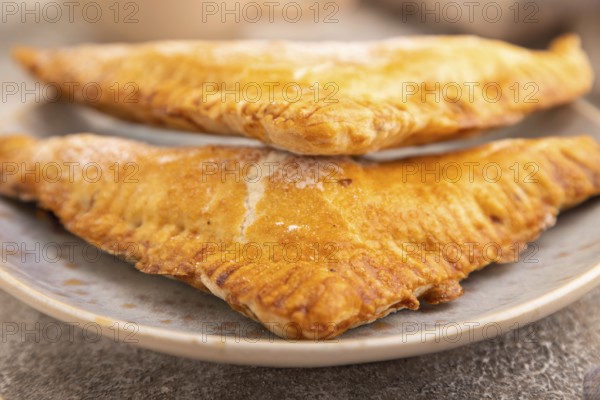 Triangles Pie, Puff Pastry, Samsa with cherry jam on brown concrete background and linen textile,