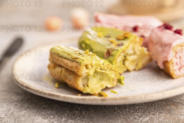 Glazed Eclairs on brown concrete background and green linen textile, cup of coffee, side view,