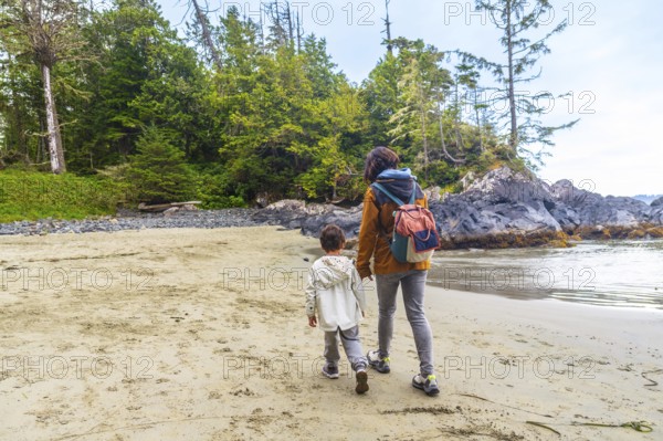 Mother and son enjoying a leisurely stroll along a beautiful sandy beach in tofino, british
