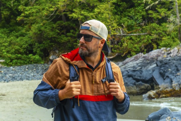 Male tourist wearing sunglasses and a baseball cap, exploring the beautiful beaches and lush