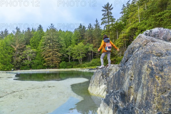 Female hiker with a backpack standing on rocks with outstretched arms, savoring the breathtaking