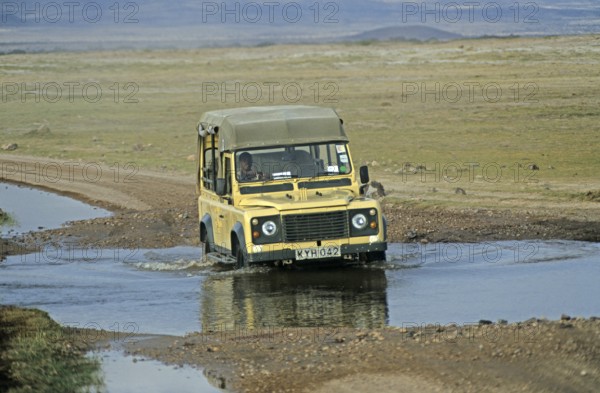 Safari vehicle driving through pools of water, Amboseli National Park, Kenya, Africa, June 2000,