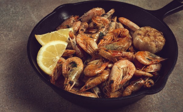 Fried shrimps, in a cast-iron pan, shrimps for beer, in a newspaper, on a gray table, there are no