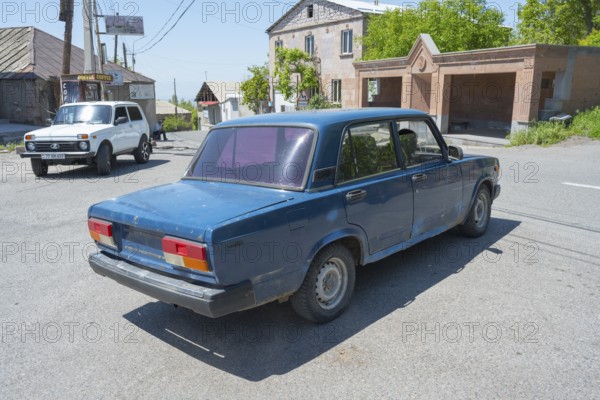 A blue car at an urban intersection on a clear sunny day, Lada 2107, also WAS-2107, VAZ-2107, Lada