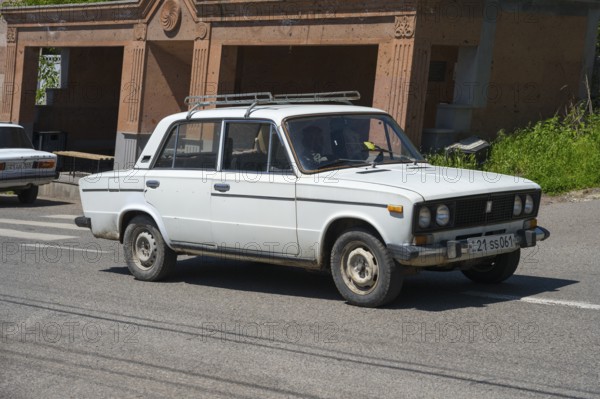 A white classic car is driving on a sunny road, Lada 1600, also VAZ-2106, Armenia