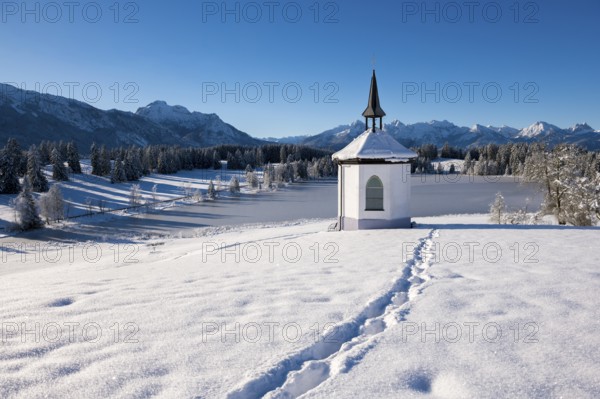 Chapel with footprints in the snow and a peaceful mountain landscape, Hegratsrieder See, near