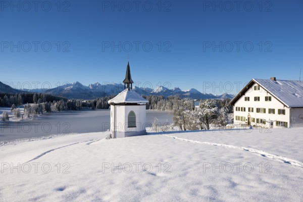 Winter scenery with chapel and house in snow-covered surroundings with mountain panorama,