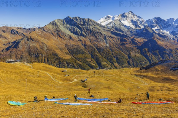 Paragliders prepare their start, summit of the Corne de Sorebois, with the backdrop of the Valais