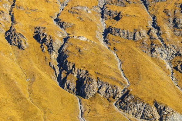 Steep and rocky mountainside in autumn colors, near the Lac de Moiry reservoir, Val d'Anniviers,