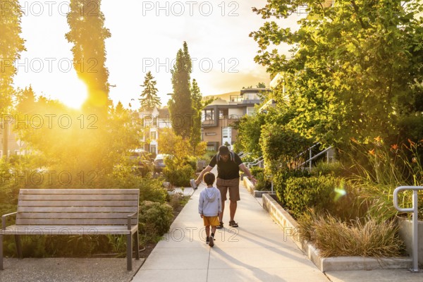 Father and son enjoying a leisurely stroll along a tree lined residential street in vancouver.