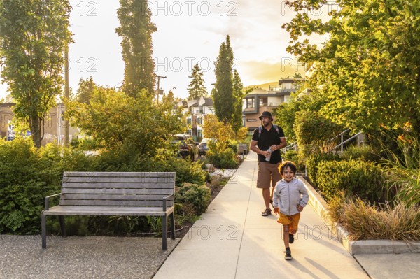Father and son are enjoying a leisurely walk through a tree lined residential street in vancouver,