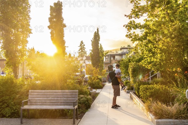 Father holding his son in a residential neighborhood of vancouver, british columbia, during a