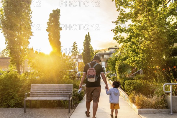 Father and son walking hand in hand at sunset in vancouver, cherishing quality moments together in