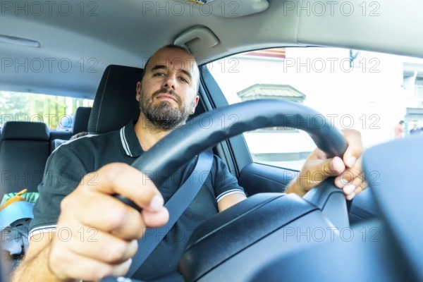 Caucasian man driving a modern car, wearing a seatbelt and holding the steering wheel, driving in