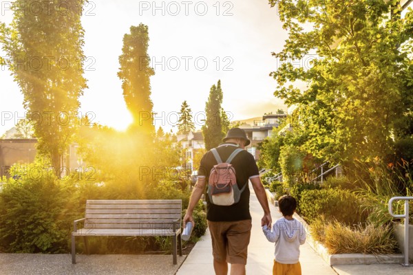 Father and son enjoying a leisurely stroll through a vancouver neighborhood at sunset, bathed in