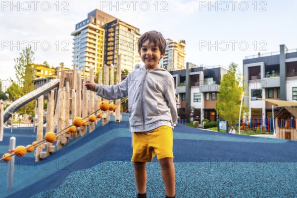 Smiling preschool child having fun in a colorful playground located in a residential area of